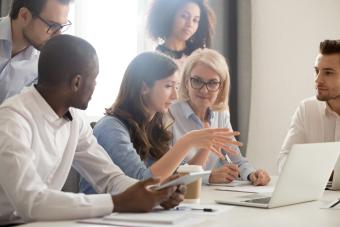 A woman explains to a group while seated with a laptop