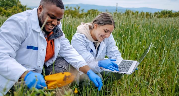 People in white coats in-a field with laptop
