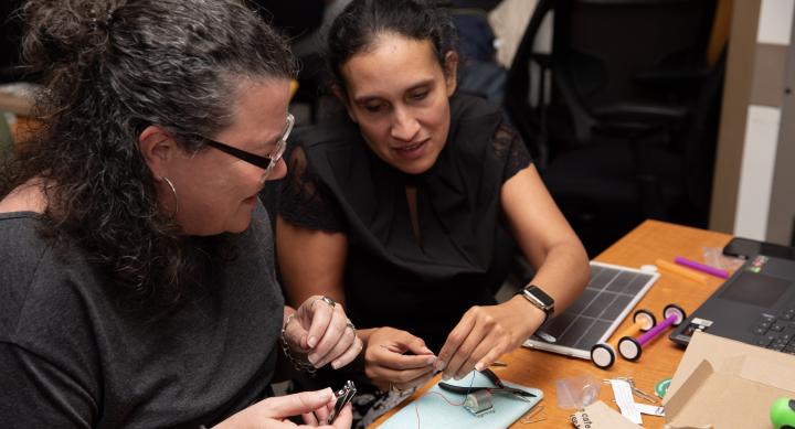 Two teachers assembling something at a table at a tech workshop